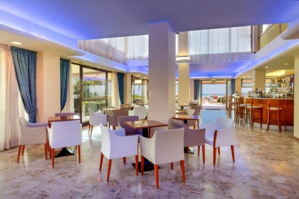 Nowoczesne wnętrze restauracji z białymi fotelami i niebieskim oświetleniem.