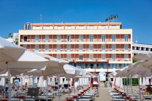 Hotel z balkonami i leżakami plażowymi pod parasolami.