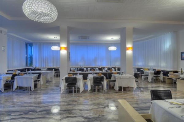 Nowoczesna restauracja z białymi obrusami i eleganckim oświetleniem.
