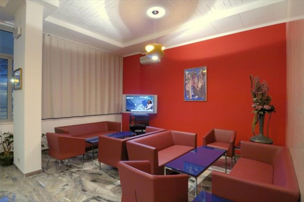 Salon z czerwonymi sofami, telewizorem i obrazem na czerwonej ścianie.