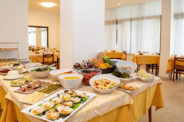 Bufetowy stół w restauracji z różnorodnymi potrawami na żółtym obrusie.  