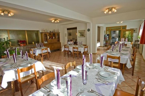 Restauracja z nakrytymi stołami i fioletowymi świecami.