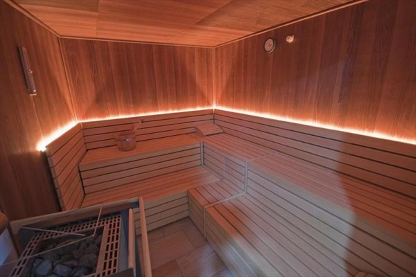 Drewniana sauna z ławkami i delikatnym oświetleniem.