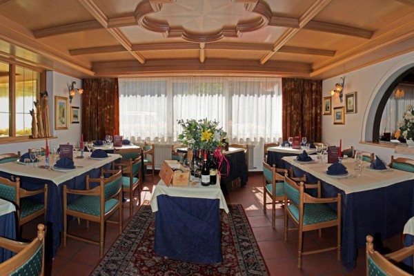 Elegancka restauracja z drewnianym sufitem, nakrytymi stołami i kwiatową dekoracją.