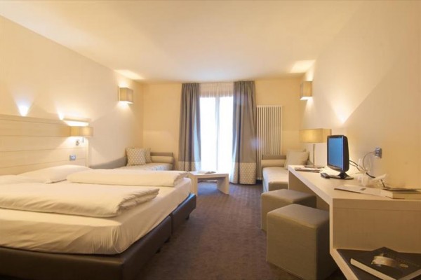 Nowocześnie urządzony pokój hotelowy z dwoma łóżkami i biurkiem.