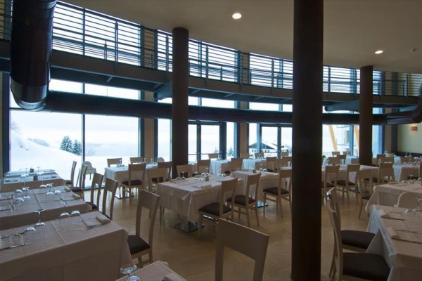Pusta restauracja ze szklanymi ścianami i ośnieżonym widokiem.