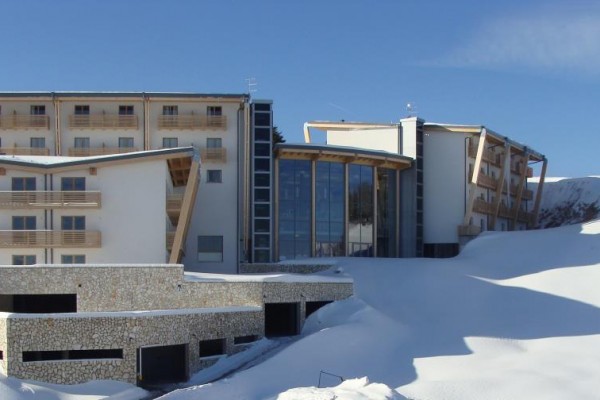 Nowoczesny budynek hotelu otoczony zaśnieżonym krajobrazem.