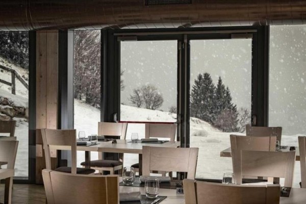 Restauracja z widokiem na zaśnieżony krajobraz przez oszklone drzwi.