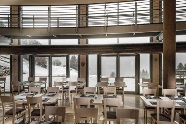 Restauracja z dużymi oknami i zaśnieżonym krajobrazem na zewnątrz.