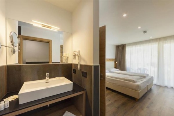 Nowoczesny pokój hotelowy z sypialnią i łazienką z umywalką i lustrem.
