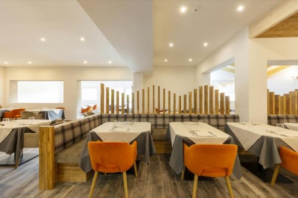 Nowoczesna restauracja z pomarańczowymi krzesłami i stołami z szarymi obrusami.