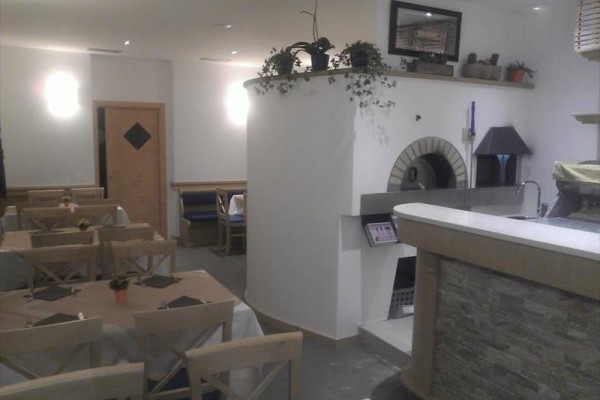 Restauracja z drewnianymi stołami i piecem do pizzy.
