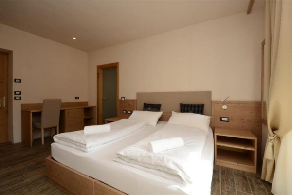 Nowoczesny pokój hotelowy z podwójnym łóżkiem, biurkiem i krzesłem.