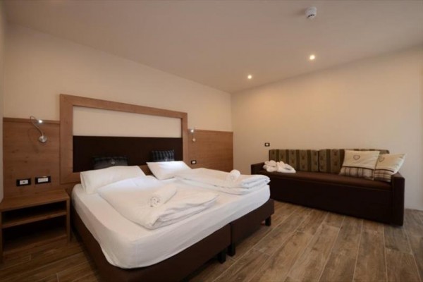 Pokój hotelowy z podwójnym łóżkiem i sofą obok.