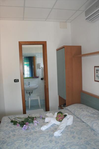 Łóżko z kwiatami i ręcznikiem w kształcie łabędzia w pokoju hotelowym.