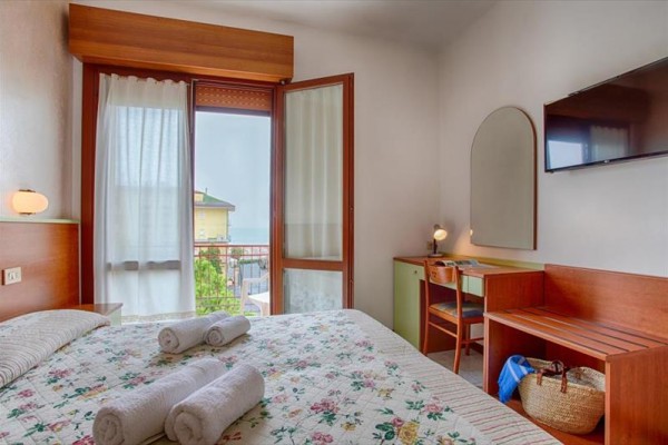 Pokój hotelowy z łóżkiem małżeńskim, balkonem i biurkiem.