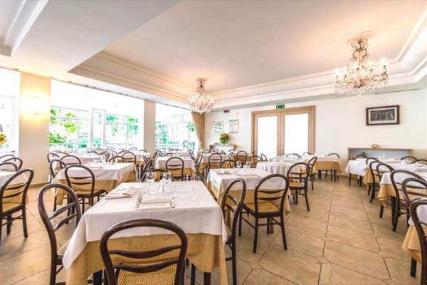 Jasna restauracja z nakrytymi stołami i drewnianymi krzesłami.