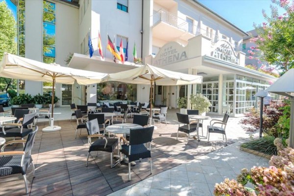 Zewnętrzna część wypoczynkowa hotelu z parasolami i krzesłami.