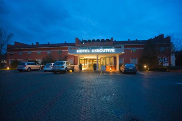 Wejście do hotelu Executive z parkingiem o zmroku.