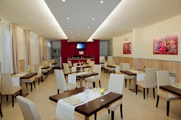 Nowoczesna restauracja z białymi krzesłami i nakrytymi stołami.
