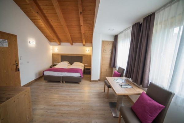 Nowoczesny pokój hotelowy z podwójnym łóżkiem, drewnianymi sufitami i biurkiem.