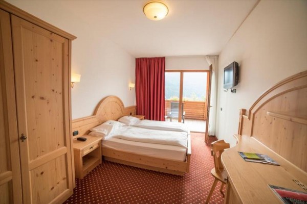 Pokój hotelowy z drewnianymi meblami, podwójnym łóżkiem i balkonem.