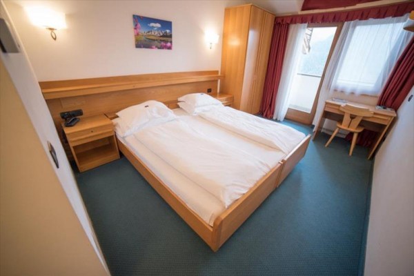Pokój dwuosobowy z drewnianymi meblami i balkonem.