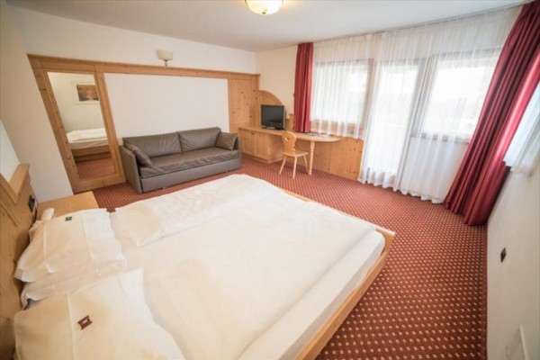 Pokój hotelowy z łóżkiem małżeńskim, sofą i biurkiem.