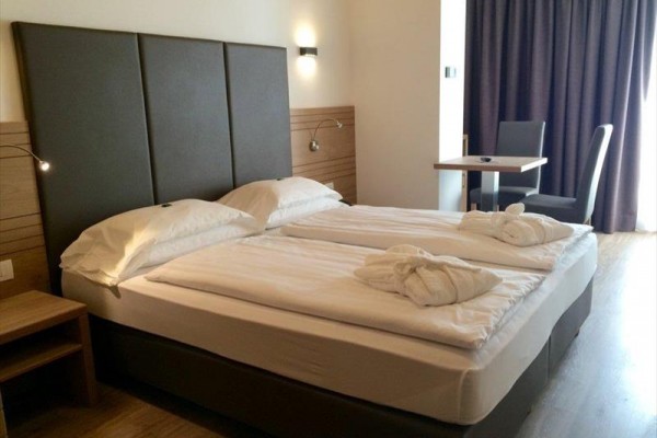 Nowoczesny pokój hotelowy z łóżkiem małżeńskim, biurkiem i krzesłami.
