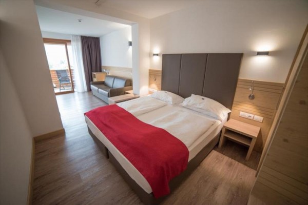Nowoczesny pokój hotelowy z łóżkiem małżeńskim, sofą i balkonem z widokiem.