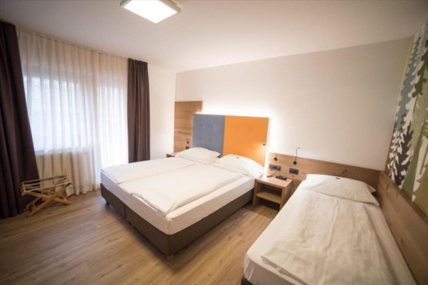 Pokój hotelowy z łóżkiem małżeńskim i jednym łóżkiem pojedynczym.