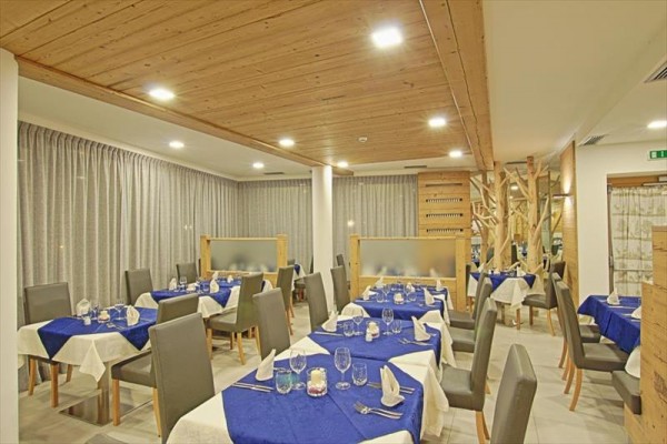 Nowocześnie urządzona restauracja z białymi i niebieskimi obrusami na stołach.