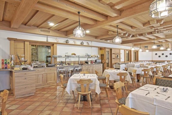 Stylowa restauracja z drewnianym sufitem i nakrytymi stołami.