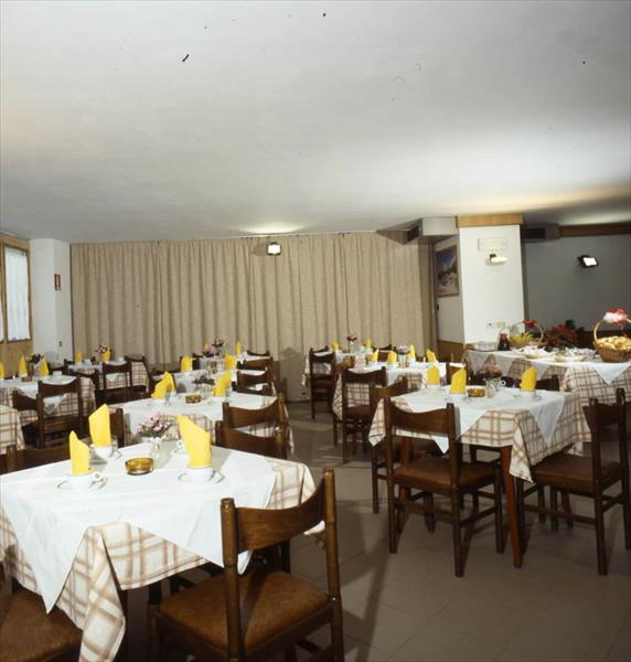 Restauracja z nakrytymi stołami, krzesłami i żółtymi serwetkami.