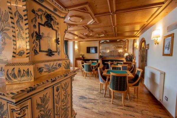 Tradycyjne wnętrze restauracji z drewnianym sufitem i zdobionym piecem kaflowym.