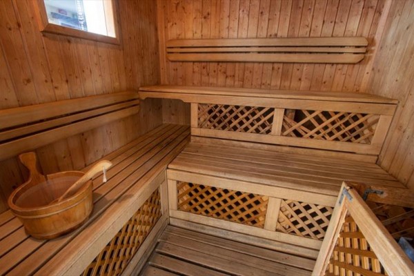 Drewniana sauna z ławkami i wiadrem na wodę.