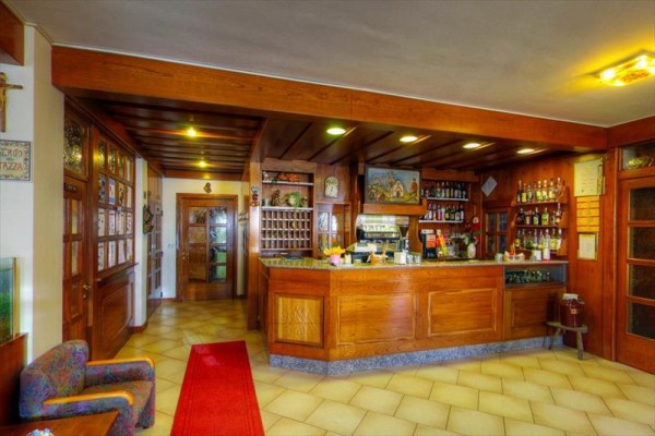 Recepcja z drewnianym ladą i regałem z napojami w hotelowym wnętrzu.