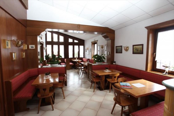 Wnętrze przytulnej restauracji z drewnianymi meblami i czerwonym obiciem.