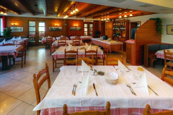 Restauracja z drewnianymi meblami i nakrytymi stołami z białymi obrusami i serwetkami.
