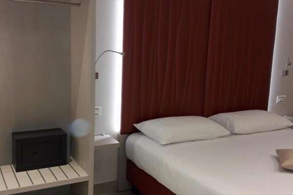 Nowoczesny pokój hotelowy z podwójnym łóżkiem i małym sejfem obok.