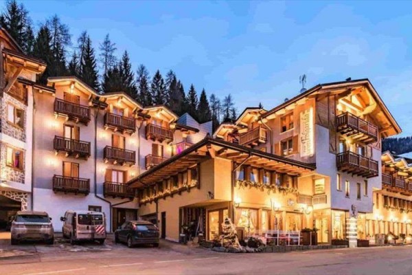 Górski hotel z drewnianymi balkonami oświetlony w zimowym krajobrazie.