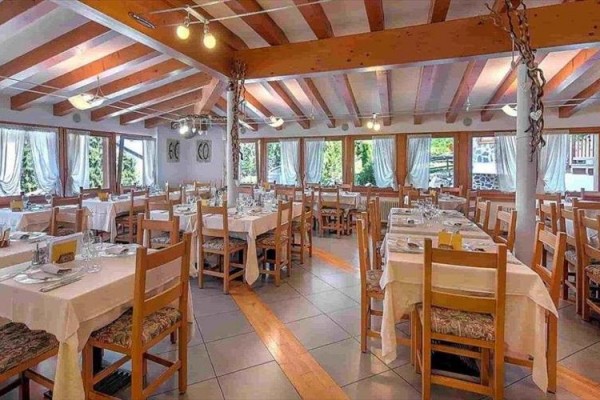 Przestronna restauracja z drewnianymi meblami i nakrytymi stołami.
