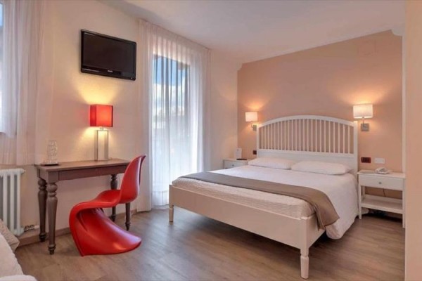 Nowoczesny pokój hotelowy z łóżkiem małżeńskim, biurkiem i czerwonym krzesłem.