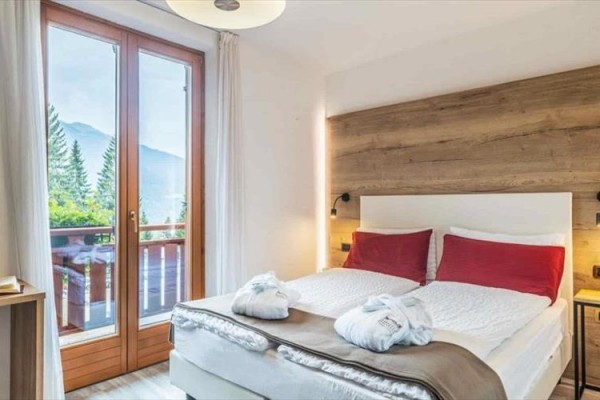 Nowoczesny pokój hotelowy z łóżkiem małżeńskim i widokiem na góry.