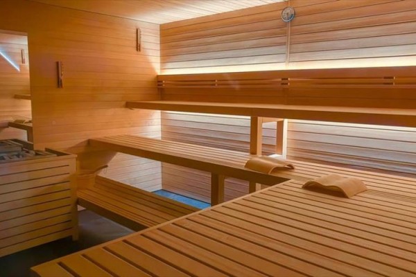 Drewniana sauna z ławkami i termometrem na ścianie.