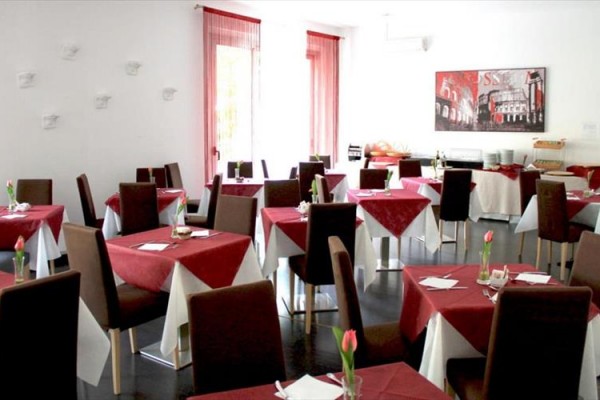 Restauracja z brązowymi krzesłami i stołami pokrytymi czerwono-białymi obrusami.