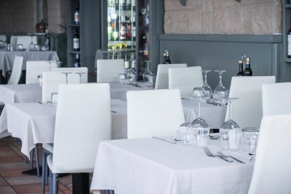 Restauracja z białymi krzesłami i nakrytymi stołami.