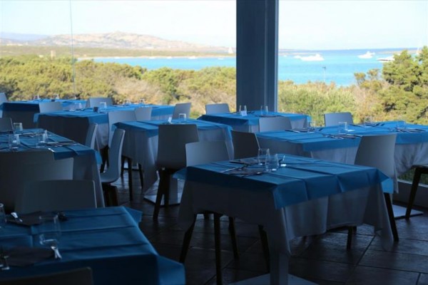 Restauracja z niebieskimi obrusami i widokiem na morze.