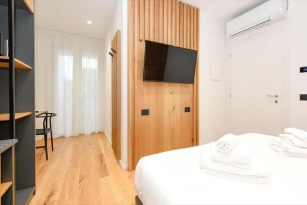 Nowoczesny pokój hotelowy z drewnianym wystrojem, podwójnym łóżkiem, telewizorem i klimatyzacją.  