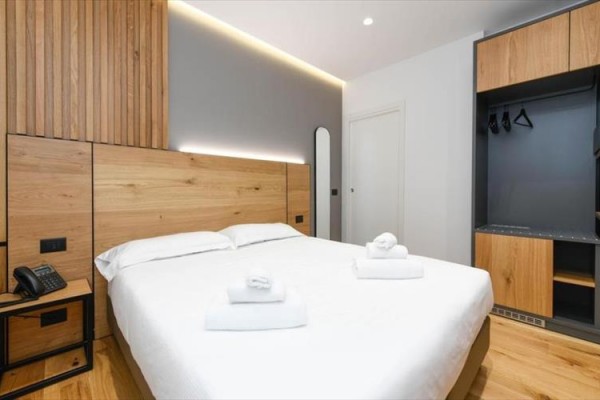 Nowoczesny pokój hotelowy z dużym łóżkiem i drewnianymi meblami.